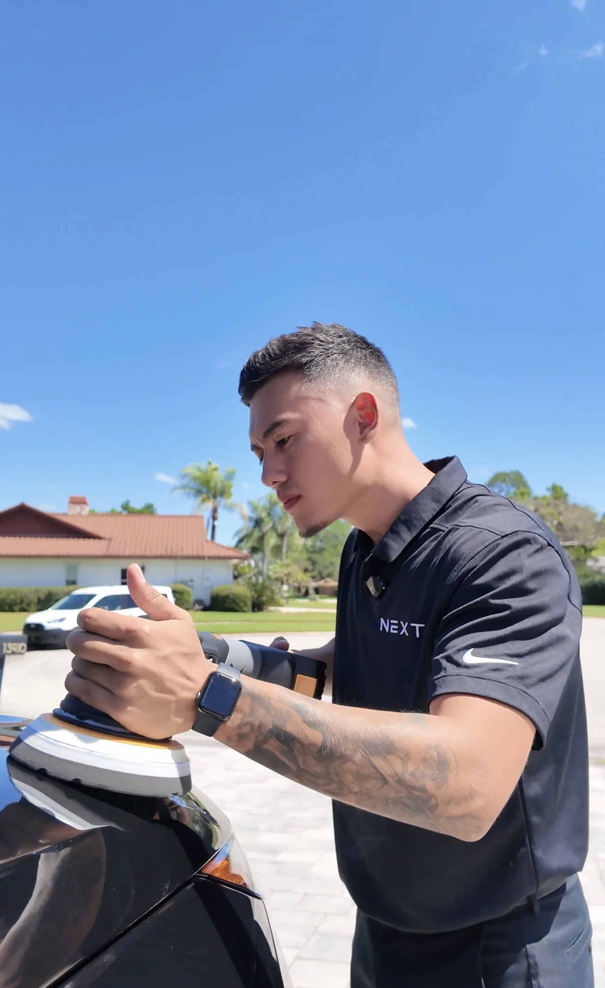 David polishing vehicle paint while wearing a NEXT-branded shirt